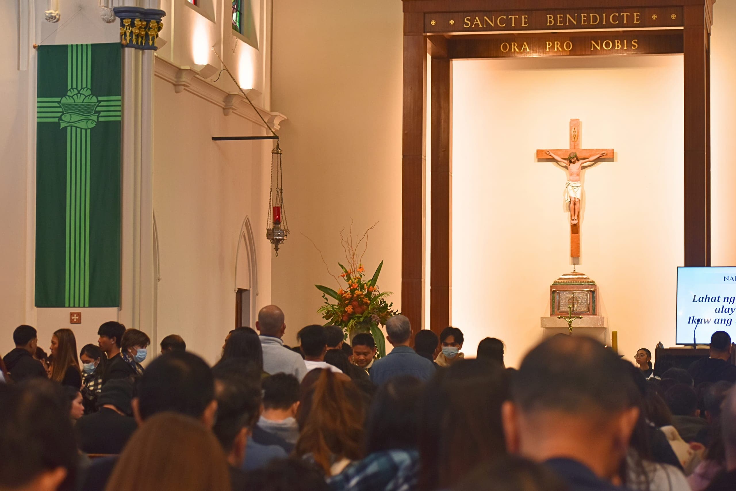 Parishioners gathered for Mass at St Benedict's Church, facing the altar and crucifix