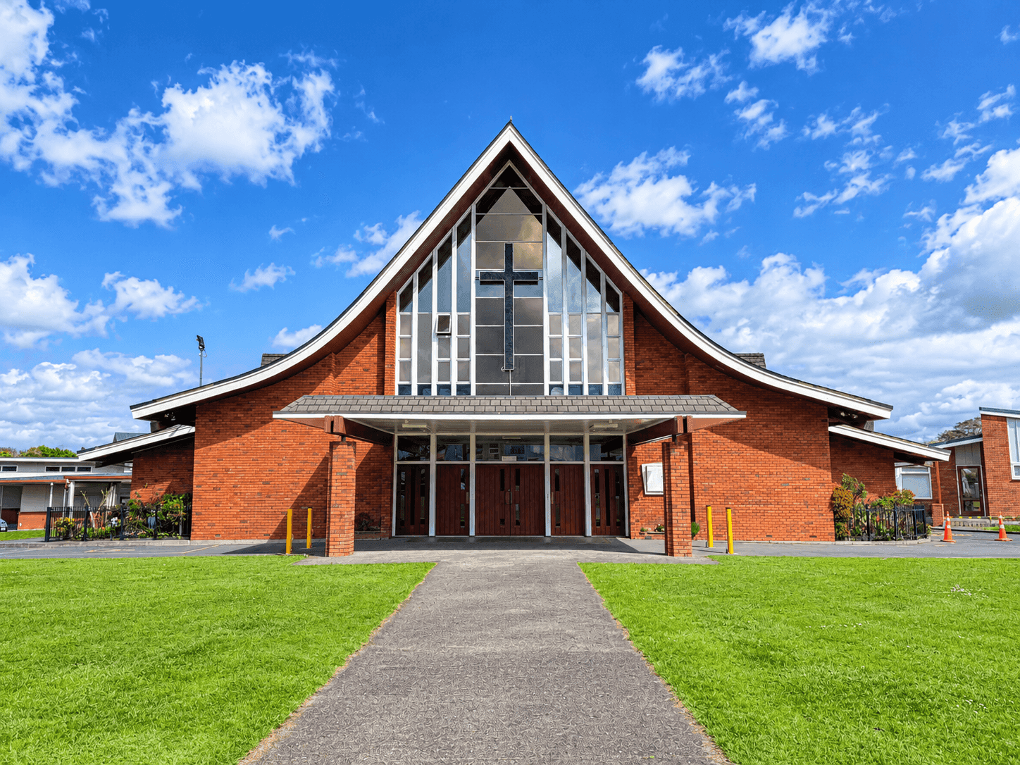 Brick Holy Cross Church with a sweeping curved roof and a path across the lawn